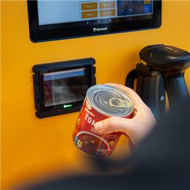 Customer using a self-service checkout with Newland hardware.