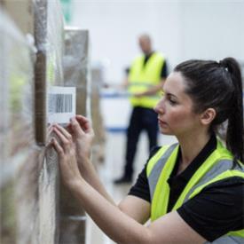 Warehouse operative applies barcode label to pallet shipment.