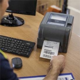 Shipping label being printed on desktop warehouse label printer from Brother.